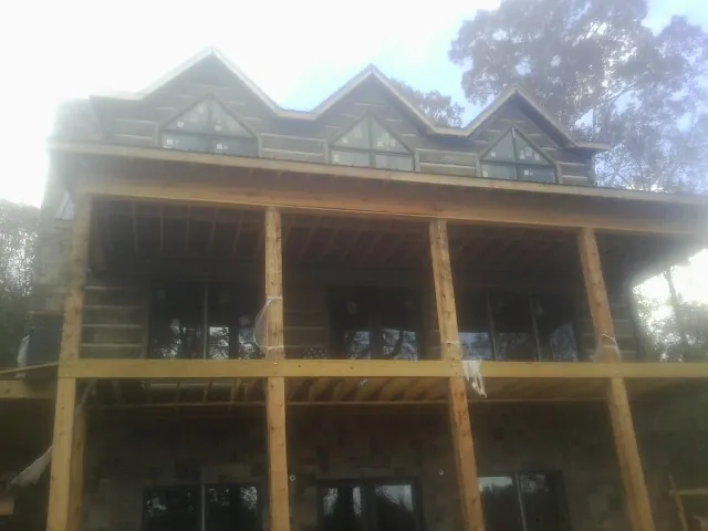 Dormers and porch framing on a large log home under construction — Roof Coating work by our crew in Buckland