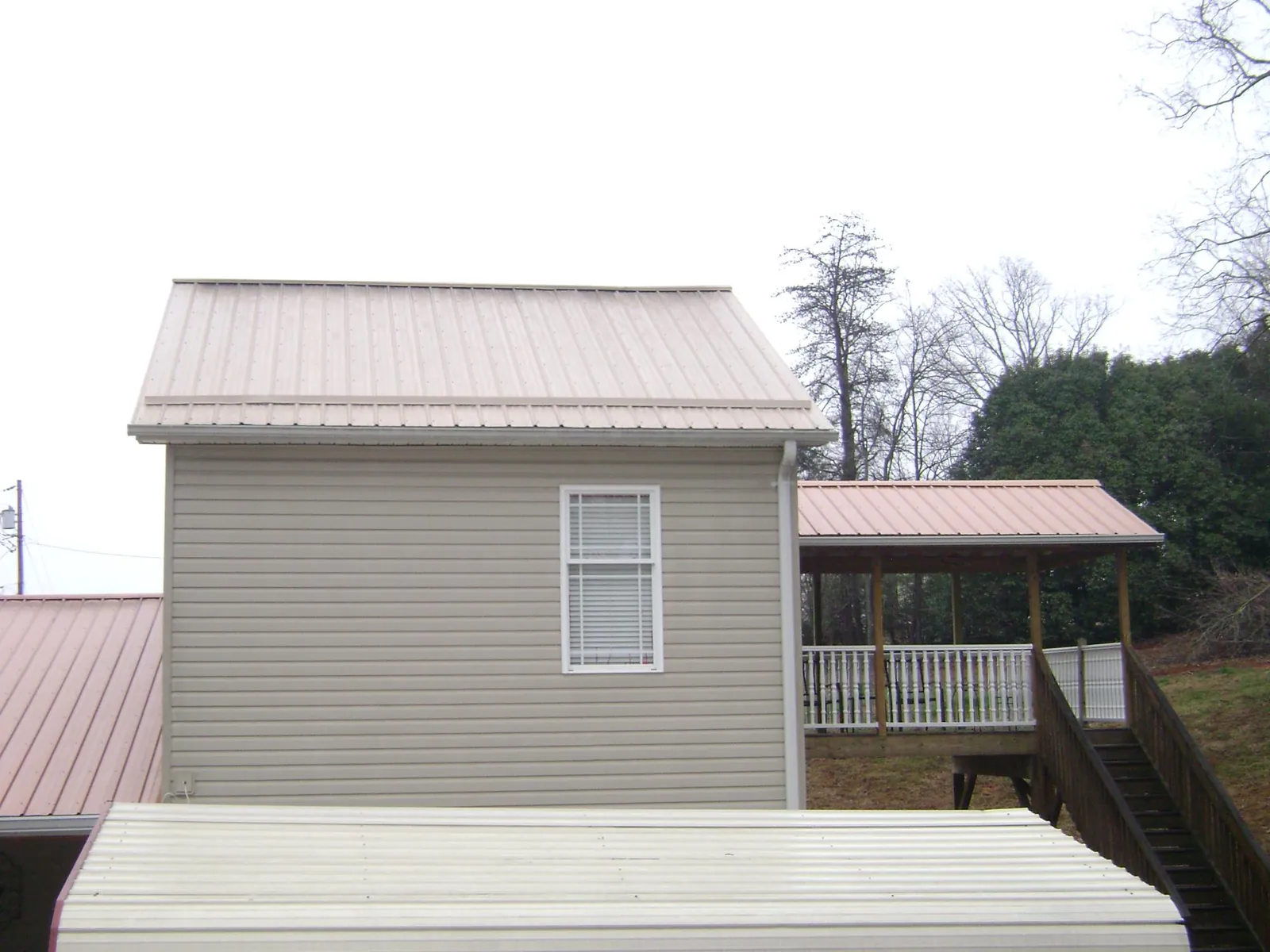 Tan metal roofs on a two story addition and attached porch, from a Roof Replacement job in Buckland